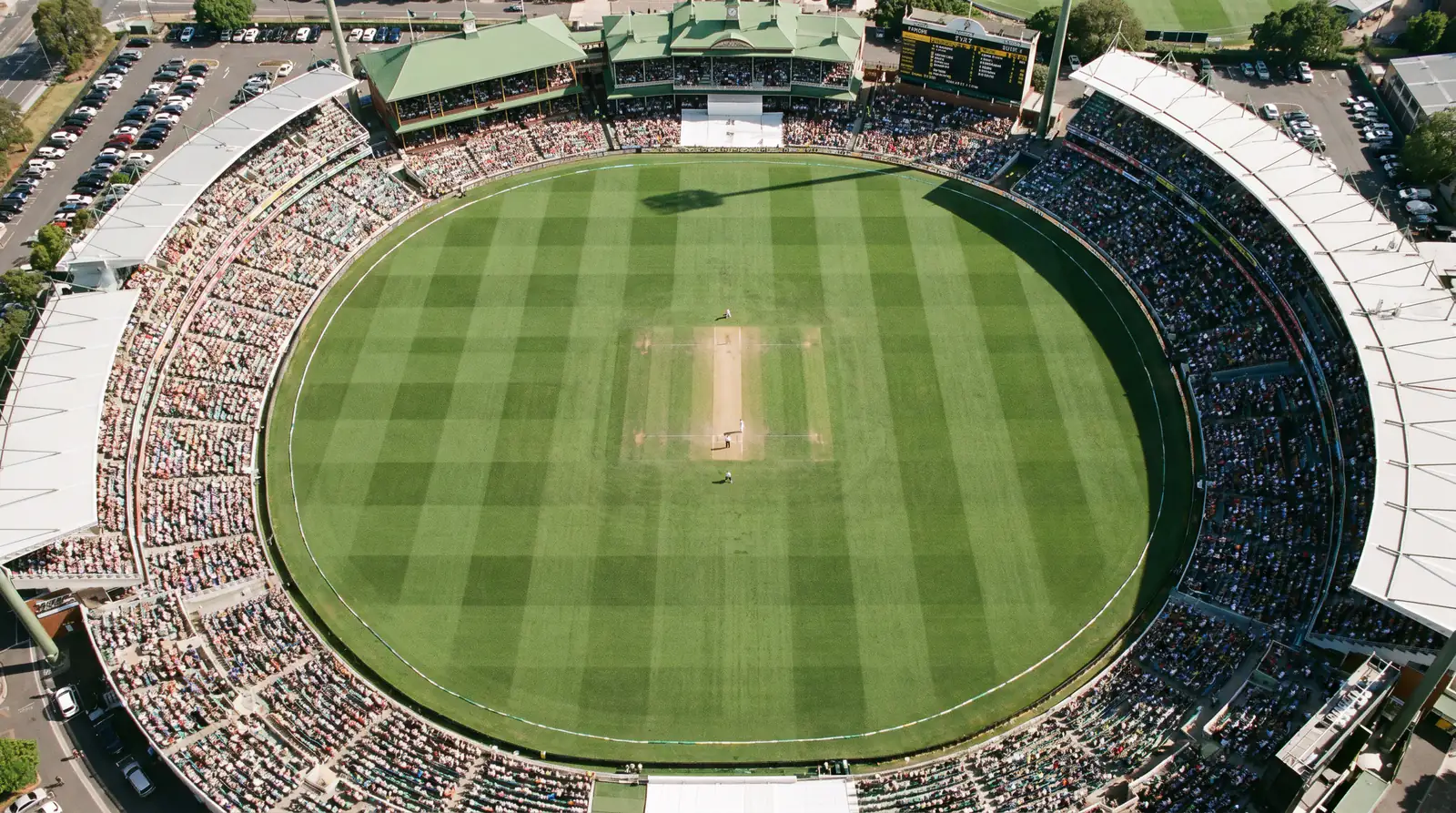 Aerial view of a cricket ground showing the oval pitch and outfield dimensions relevant to scoring patterns
